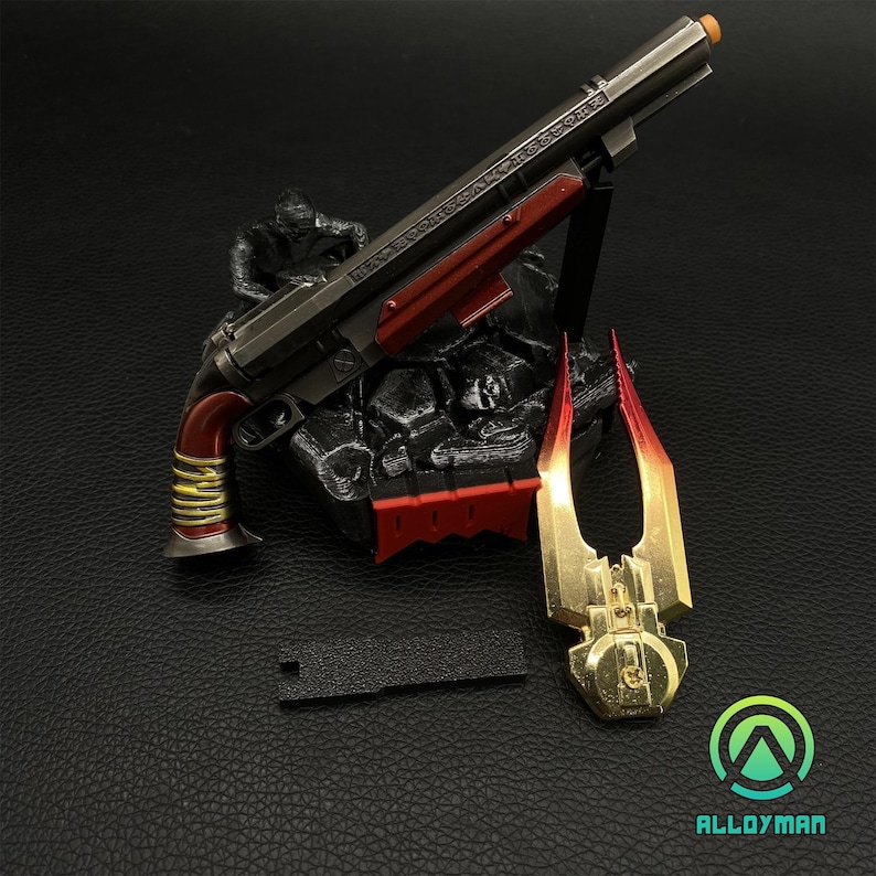 Pu&ograve; includere: Una replica di fucile a pompa in metallo nero e rosso con un'impugnatura dorata, una replica di lama in metallo rosso e oro e un supporto in plastica nera.