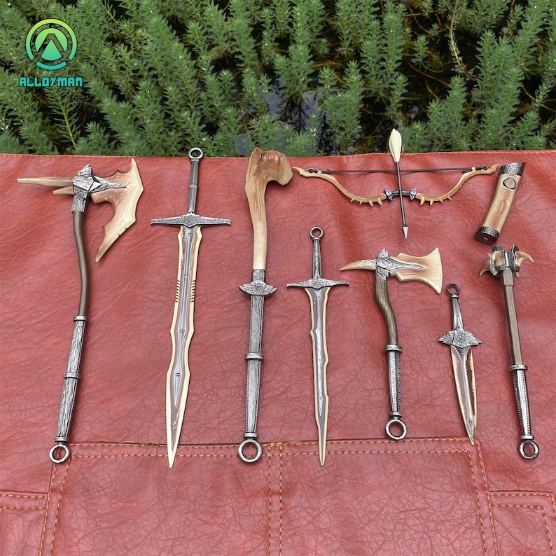 Puede incluir: Una colecci&oacute;n de armas de fantas&iacute;a, incluyendo espadas, hachas, un arco y flechas, y una maza, se exhibe sobre una superficie roja. Las armas presentan elementos met&aacute;licos y de madera, con dise&ntilde;os intrincados. La imagen muestra una variedad de armamento de inspiraci&oacute;n medieval.