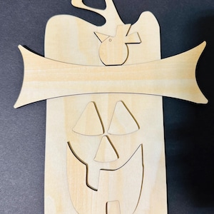 May include: A wooden pumpkin-shaped cutout with a jack-o'-lantern face, a banner, and a bird. The pumpkin's face is cut out, and the banner is curved. The bird is perched on top of the pumpkin. Perfect for Halloween decorations.