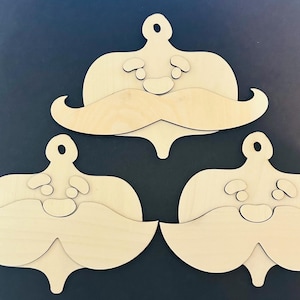 May include: Three unfinished wooden Santa Claus ornaments. Each ornament features a round top with a hole for hanging, a face with a mustache, and a decorative bottom. The ornaments are made of light-colored wood.