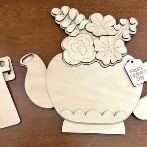 May include: Wooden craft kit featuring a teapot with flowers and a tag that says "Happy Mother's Day".