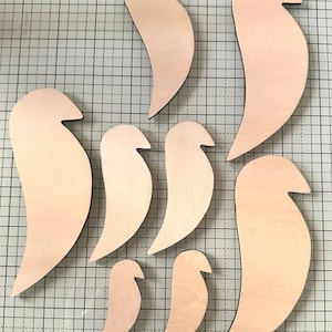 May include: Seven wooden bird shapes in various sizes, all cut in the same style. The shapes are light brown and have a smooth, unfinished surface.