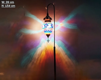 May include: A floor lamp with a mosaic glass shade in shades of blue, green, and white. The lamp is on a metal stand and has a curved arm. The lamp is casting a colorful light on the wall behind it. W: 39 cm H: 154 cm