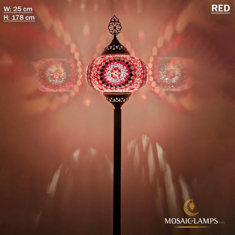 May include: A red mosaic glass floor lamp with a round shade and a decorative metal base. The lamp is 25 inches wide and 70 inches tall. The lamp is lit and casting a warm glow on the wall behind it.