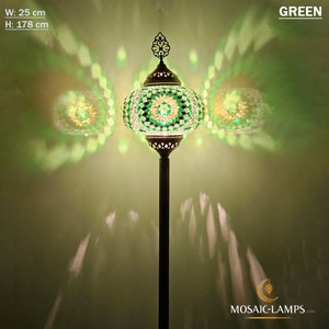 May include: A green mosaic floor lamp with a round shade and a decorative finial. The lamp is 25 inches wide and 70 inches tall. The lamp is lit and casting a warm glow.