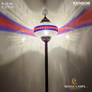 May include: A white mosaic floor lamp with a blue, red, and orange geometric pattern. The lamp is 25 inches wide and 70 inches tall. The lamp is lit and casting a rainbow-colored light on the wall behind it.