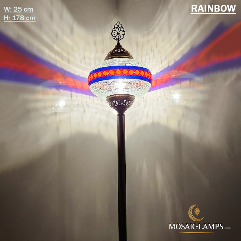 May include: A white mosaic floor lamp with a blue, red, and orange geometric pattern. The lamp is 25 inches wide and 70 inches tall. The lamp is lit and casting a rainbow-colored light on the wall behind it.