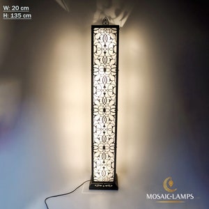 May include: A tall, black metal floor lamp with a white, intricate, geometric pattern. The lamp is 135 cm tall and 20 cm wide.