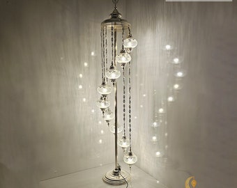 May include: A tall, silver floor lamp with multiple cracked blown glass globes hanging from a circular top. The lamp is 197 cm tall and 50 cm wide. The text "CRACKED BLOWN GLASS" is visible at the top. The base has the logo "MOSAIC-LAMPS".