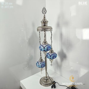 Op de afbeelding: Een zilveren staande lamp met drie blauwe mozaïekglazen bollen. De lamp is 35 cm breed en 107 cm hoog.  BLUE.