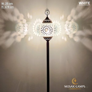 May include: White mosaic glass floor lamp with a round shade and a decorative finial. The lamp is 25 inches wide and 70 inches tall.  The lamp is lit and casting a warm glow.