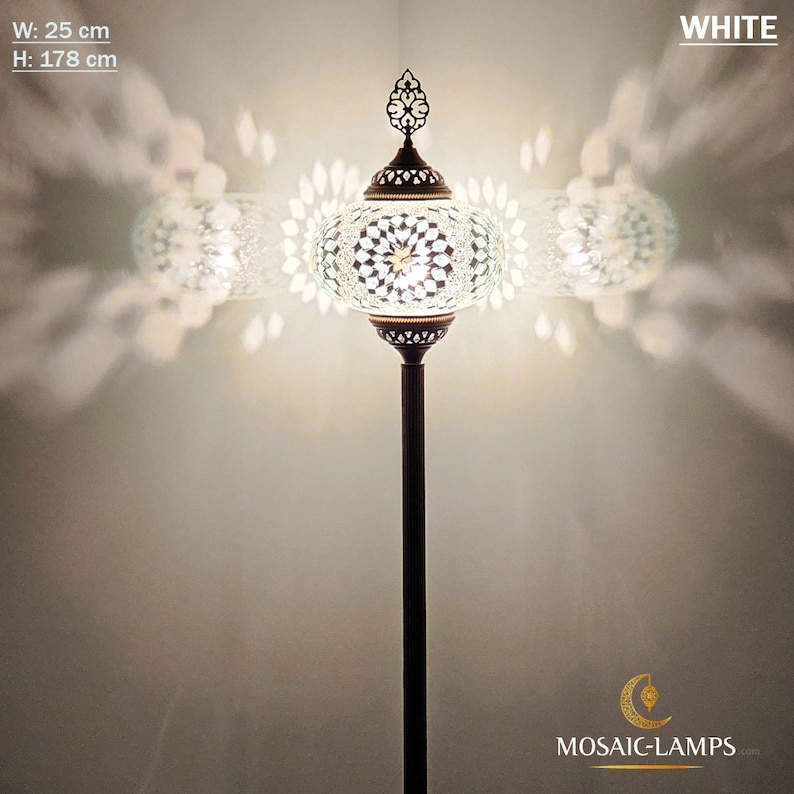 May include: White mosaic glass floor lamp with a round shade and a decorative finial. The lamp is 25 inches wide and 70 inches tall.  The lamp is lit and casting a warm glow.