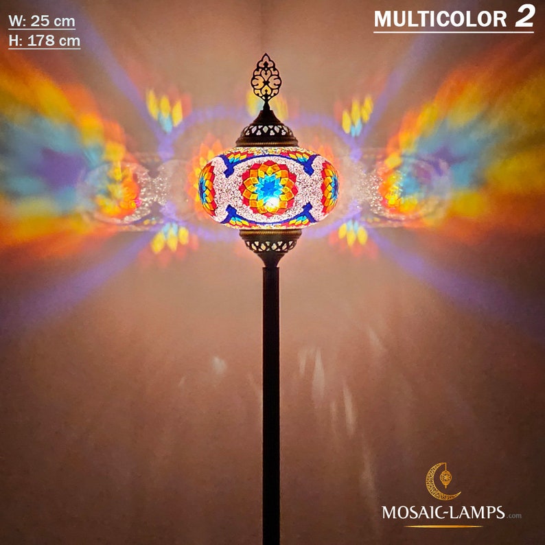 May include: A colorful mosaic glass floor lamp with a round shade and a black metal stand. The lamp is lit and casting a rainbow of colors on the wall. The lamp is 25 inches wide and 70 inches tall. MULTICOLOR 2