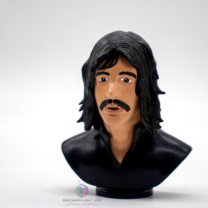 May include: A black and white 3D printed bust of a man with long black hair and a mustache. The bust is on a small black base.