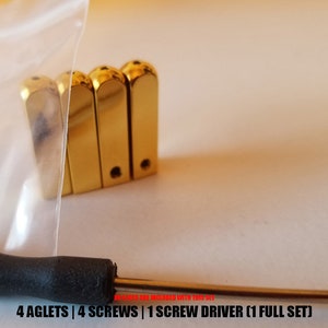 May include: Four gold-colored aglets, four screws, and a small screwdriver. The text "LUXURY-AGLETS" is visible on the right side of the image. The text "4 AGLETS | 4 SCREWS | 1 SCREW DRIVER (1 FULL SET)" is visible at the bottom of the image.