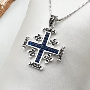May include: A silver pendant necklace with a blue and silver cross pendant. The cross is decorated with small silver accents and blue stones.
