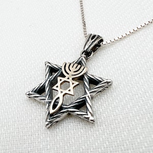 May include: A silver Star of David pendant necklace with a gold menorah and Star of David design. The pendant is on a silver chain.