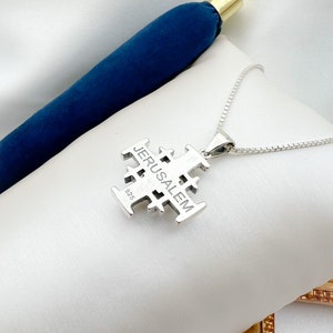Pu&ograve; includere: Una collana d'argento con un ciondolo a forma di croce di Gerusalemme. Il ciondolo &egrave; inciso con la parola "Gerusalemme" e il numero "925".