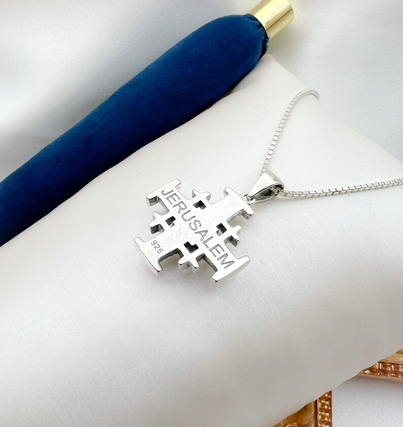 Pu&ograve; includere: Una collana d'argento con un ciondolo a forma di croce di Gerusalemme. Il ciondolo &egrave; inciso con la parola "Gerusalemme" e il numero "925".