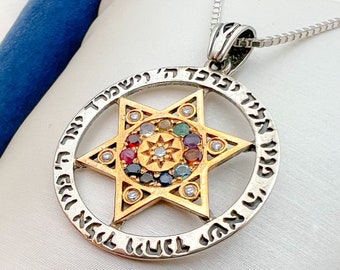 Op de afbeelding: Een zilveren ketting met een gouden hanger met een Davidster met een cirkel van gekleurde edelstenen rond het midden. De hanger is beschreven met Hebreeuwse tekst.
