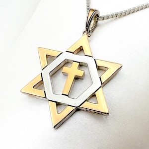 May include: A silver and gold pendant necklace featuring a Star of David with a cross inside. The pendant is marked with "M 925".