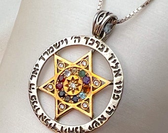 Op de afbeelding: Een zilveren ketting met een gouden hanger met een Davidster met een cirkel van gekleurde edelstenen rond het midden. De hanger is beschreven met Hebreeuwse tekst: "פניו אליך יברכך ה' וישמרך רד יאר ה' פניו אליך ויחנך ישא הי"