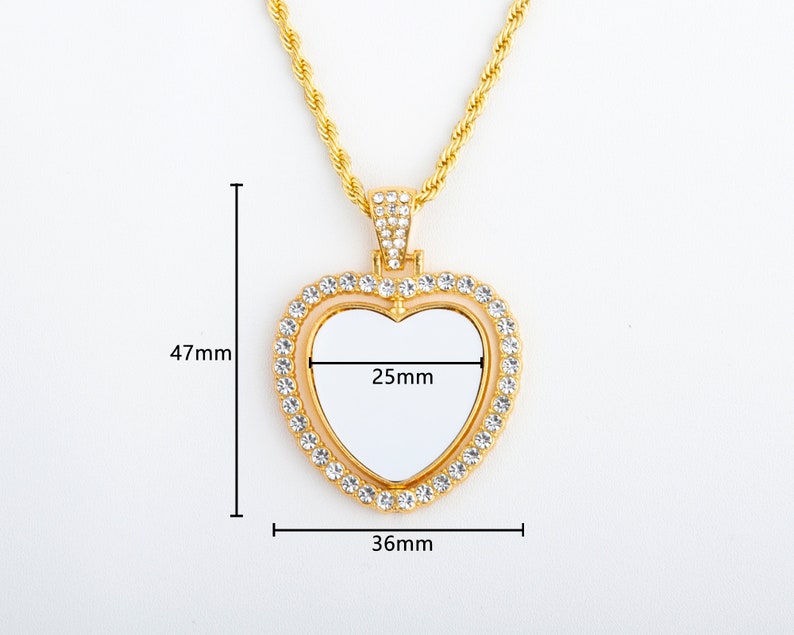 May include: Gold heart-shaped pendant necklace with a clear, blank space in the centre. The pendant is decorated with clear rhinestones and measures 36mm wide and 47mm tall. The pendant has a 25mm wide opening in the centre.