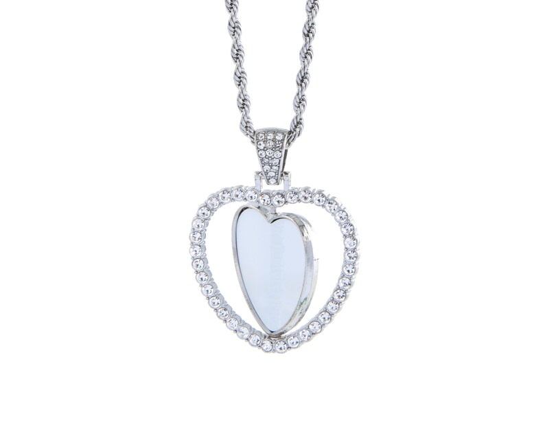 May include: A silver necklace with a heart-shaped pendant. The pendant is surrounded by small clear rhinestones and has a smaller heart-shaped cutout in the centre.