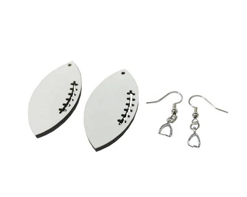 May include: A pair of white football-shaped earrings with black stitching detail. The earrings are attached to silver-toned ear wires.