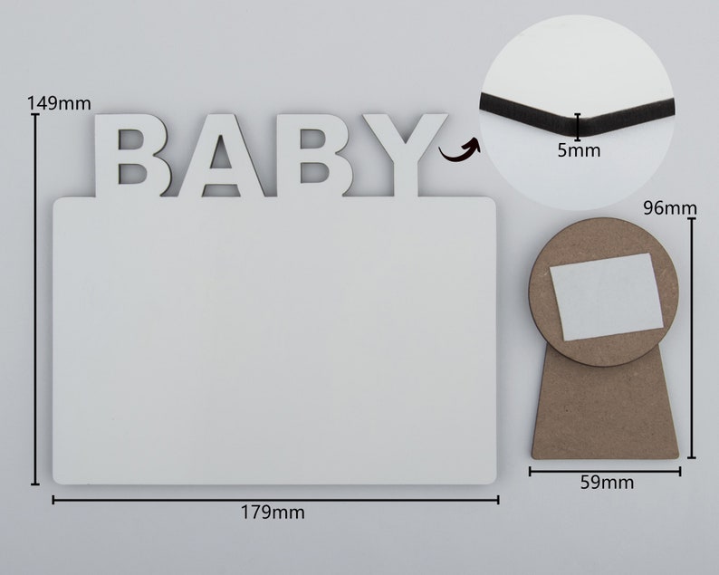 May include: A white rectangular photo frame with the word "BABY" in white letters at the top. The frame is 179mm wide and 149mm tall. A round stand is attached to the back, 59mm wide and 96mm tall.