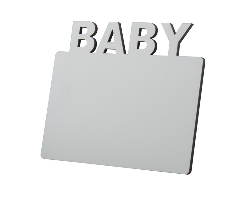 May include: A white rectangular sign with the word "BABY" in capital letters at the top. The sign has a black border and is angled slightly towards the viewer, set against a white background.