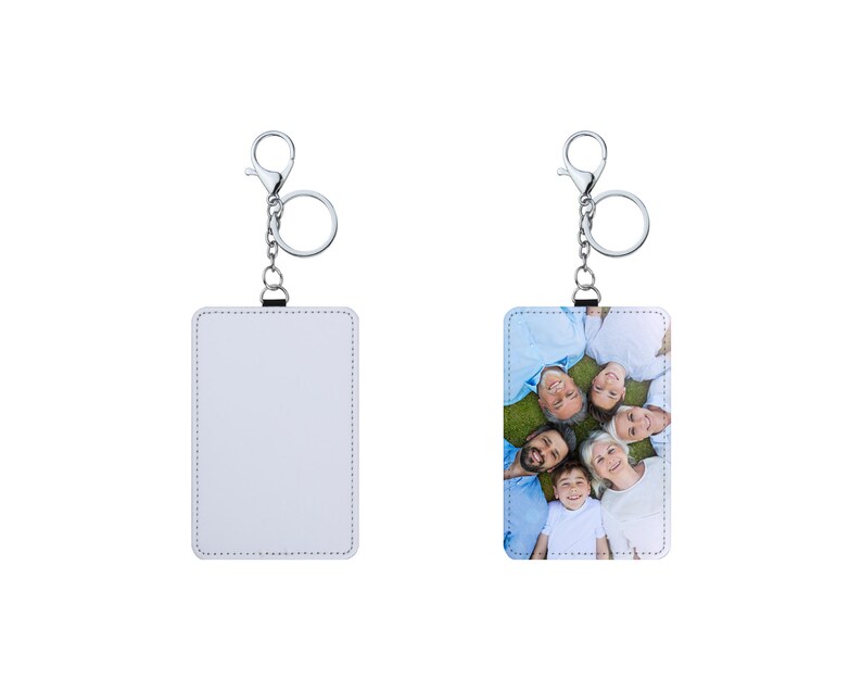 May include: Two white leather keychains with silver key rings. One keychain has a blank white surface and the other has a photo of a family of six smiling and lying on their backs on a grassy lawn.