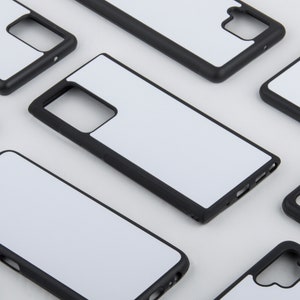 May include: Multiple black phone cases with white blank inserts. The cases are designed to protect a smartphone.