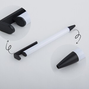 May include: A white pen with a black retractable tip and a black stand that can be used as a phone holder. The stand is attached to the pen and can be rotated.