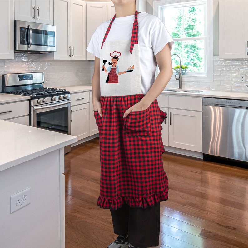 May include: A red and black checkered apron with a white ruffle trim and two pockets. The apron has a white bib with a cartoon chef illustration and the text "I'm a Chef".
