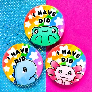 Pode incluir: Três botões coloridos com fundos de arco-íris e estrelas brancas. Cada botão apresenta um animal diferente: um sapo, um dinossauro e um axolote. O texto em cada botão diz "I Have Did".