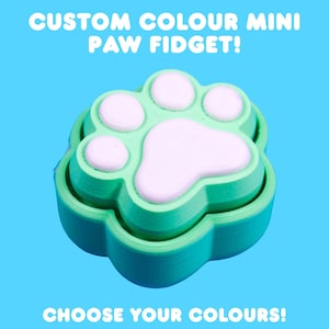 May include: A custom color mini paw fidget toy in shades of green and white, set against a bright blue background. The text "CUSTOM COLOUR MINI PAW FIDGET!" and "CHOOSE YOUR COLOURS!" are displayed in white.