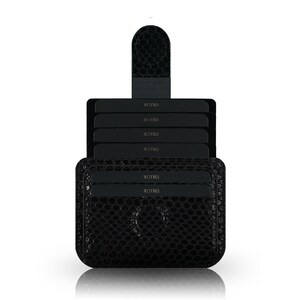 May include: Black leather card holder with a textured, crocodile-like pattern. The holder has a flap with a snap closure and multiple slots for cards. The text "ROTIKS" is embossed on the cards.