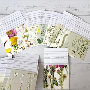 May include: A selection of library cards with botanical illustrations. The cards display floral and plant designs, including images of thistles, pondweeds, and wintergreens. Each card has spaces for author, title, and due date.