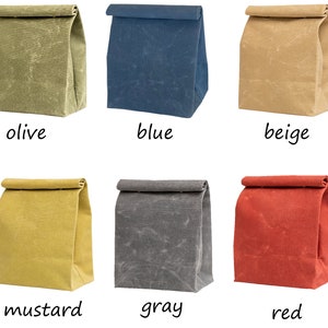 May include: Six canvas lunch bags in different colors: olive, blue, beige, mustard, gray, and red. The bags are folded and laid out on a white background.
