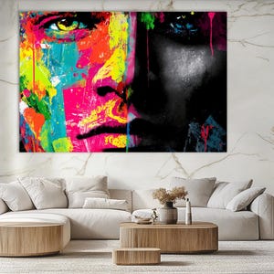 Könnte beinhalten: Leinwanddruck mit abstrakter Kunst, die ein geteiltes Gesicht darstellt. Eine Seite ist lebendig mit Neonfarben, die andere in Schwarz und Weiß. Das Kunstwerk zeigt einen modernen, ausdrucksstarken Stil, ideal für die Inneneinrichtung.