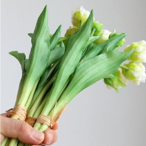 Op de afbeelding: Een boeket van witte en groene kunstmatige tulpen met groene stelen die met touw aan elkaar zijn gebonden.