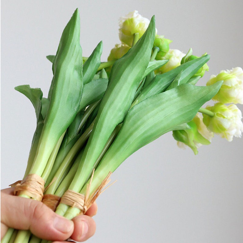 Op de afbeelding: Een boeket van witte en groene kunstmatige tulpen met groene stelen die met touw aan elkaar zijn gebonden.