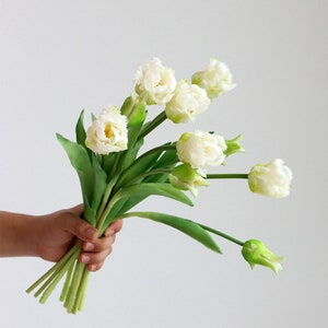 Op de afbeelding: Een boeket witte kunsttulpen met groene stelen. De tulpen hebben gekrulde bloemblaadjes en zijn gerangschikt in een handboeket.