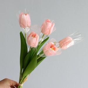May include: A bouquet of five pink artificial tulips wrapped in clear plastic.