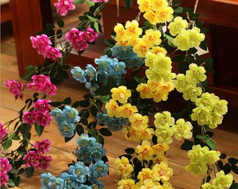 Puede incluir: Un ramo de flores artificiales con flores rosas, amarillas, azules y verdes. Las flores están dispuestas sobre una superficie de madera y tienen un aspecto realista.