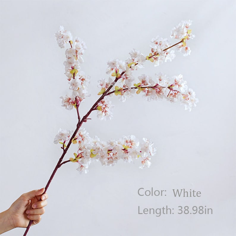 May include: A single white artificial cherry blossom branch with pink accents. The branch is 38.98 inches long.
