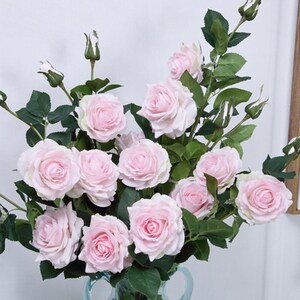 May include: A bouquet of pink artificial roses with green leaves and stems. The roses are arranged in a vase.