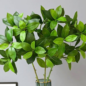 May include: A bunch of artificial green leaves with a natural look, perfect for adding greenery to a home or office.
