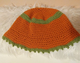 May include: A crocheted hat with a wide brim, featuring a bright orange body and a green trim around the brim and crown.